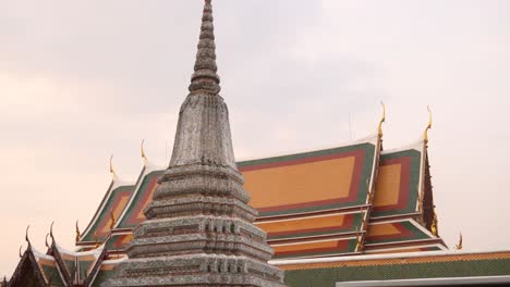 Aguja-Budista-Frente-Al-Techo-Naranja-De-Un-Templo-En-El-Casco-Antiguo-De-Rattanakosin-En-Bangkok,-Tailandia