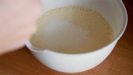 adding flour to batter in a white bowl
