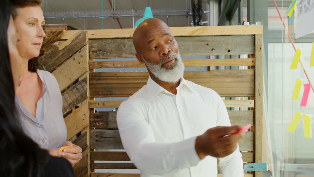 ejecutivos discutiendo sobre una nota adhesiva en la pared de vidrio 4k