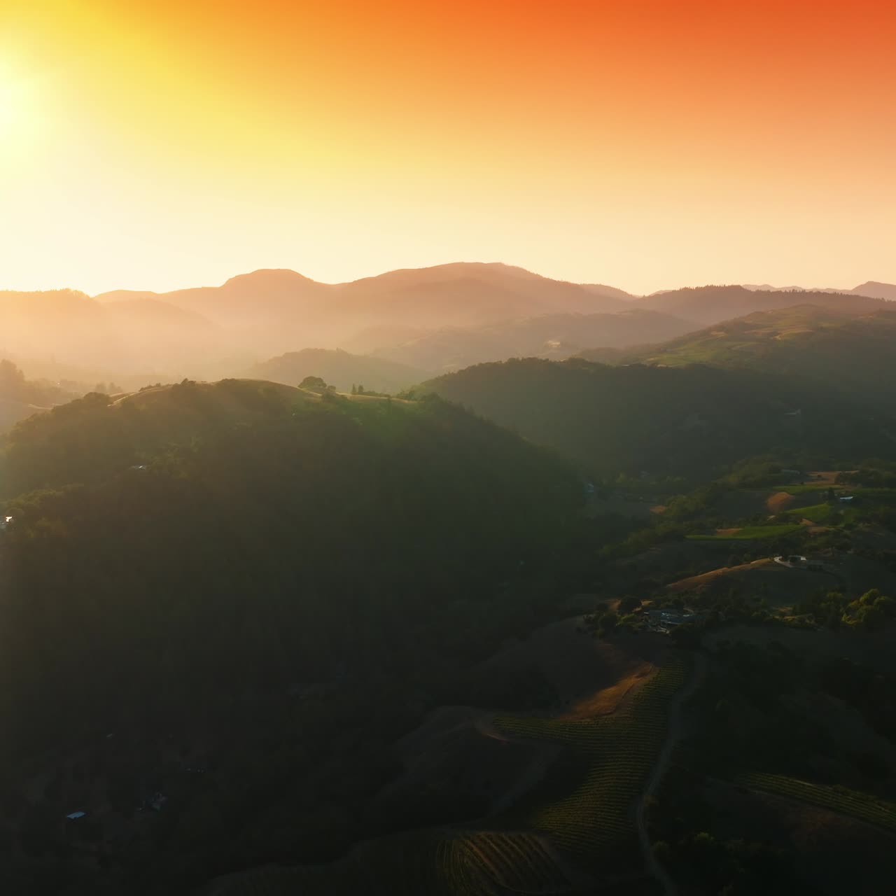 Picturesque green mountains of Napa, California, USA. Amazing vineyards from aerial perspective at setting sun. Orange sky at backdrop