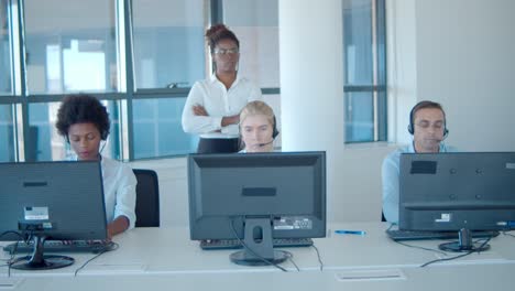 strict female boss behind the call center employees, keeping an eye on them