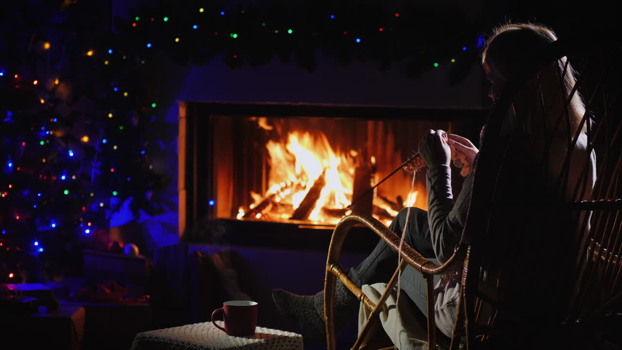 вид сзади на женщину, которая вяжет, сидя у камина 4k видео