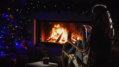 vista trasera de una mujer tejiendo mientras está sentada junto a la chimenea 4k video