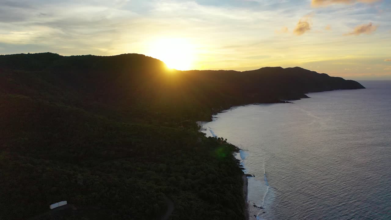 Golden sunrise over the calm Caribbean in St. Croix, where soft morning light reveals a secluded peninsula, tall trees swaying gently, and the shoreline basking in island serenity