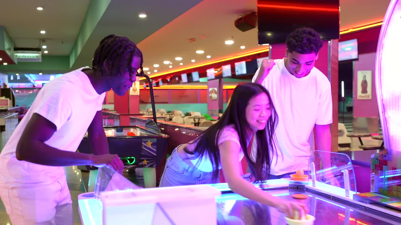 People having fun in an arcade playing air hockey