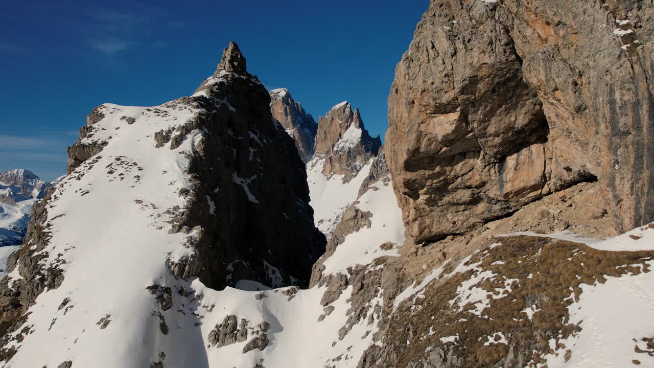 은 파란 하늘을 배경으로 아있는 눈이 쌓인 바위 산꼭대기의 역동적인 비행은 알파인 모험의 본질을 포착합니다.
