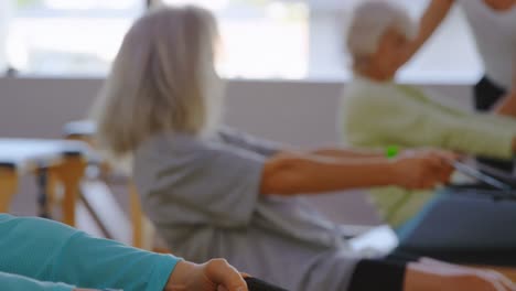 Trainer-assisting-senior-women-while-stretching-exercise-4k