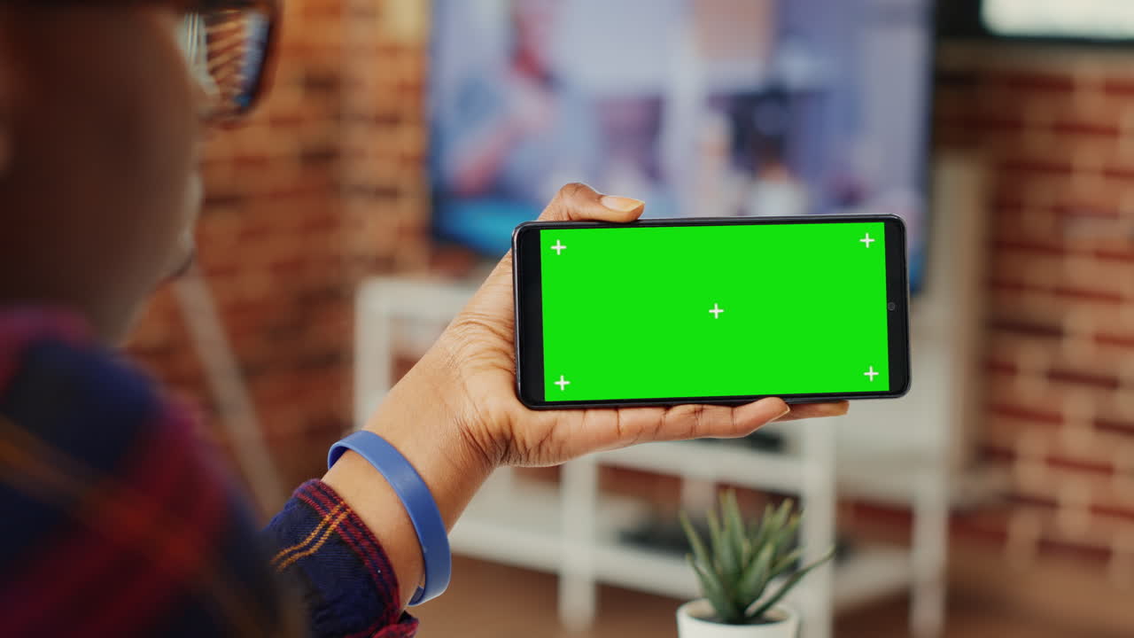 Young adult looking at horizontal greenscreen on telephone