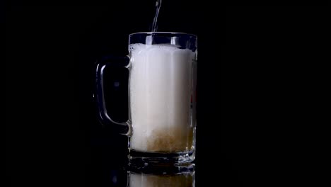 slow motion shot of pouring beer in a mug until it spills over