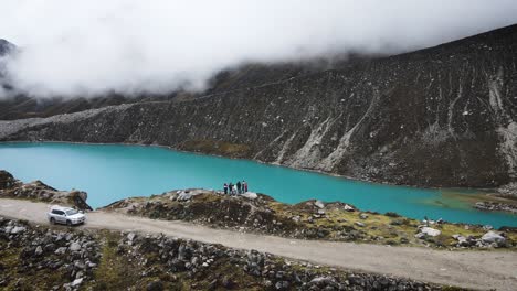 Dron-Dando-Vueltas-A-Un-Grupo-De-Amigos-En-Una-Laguna-Azul-En-Las-Montañas-De-Huaraz