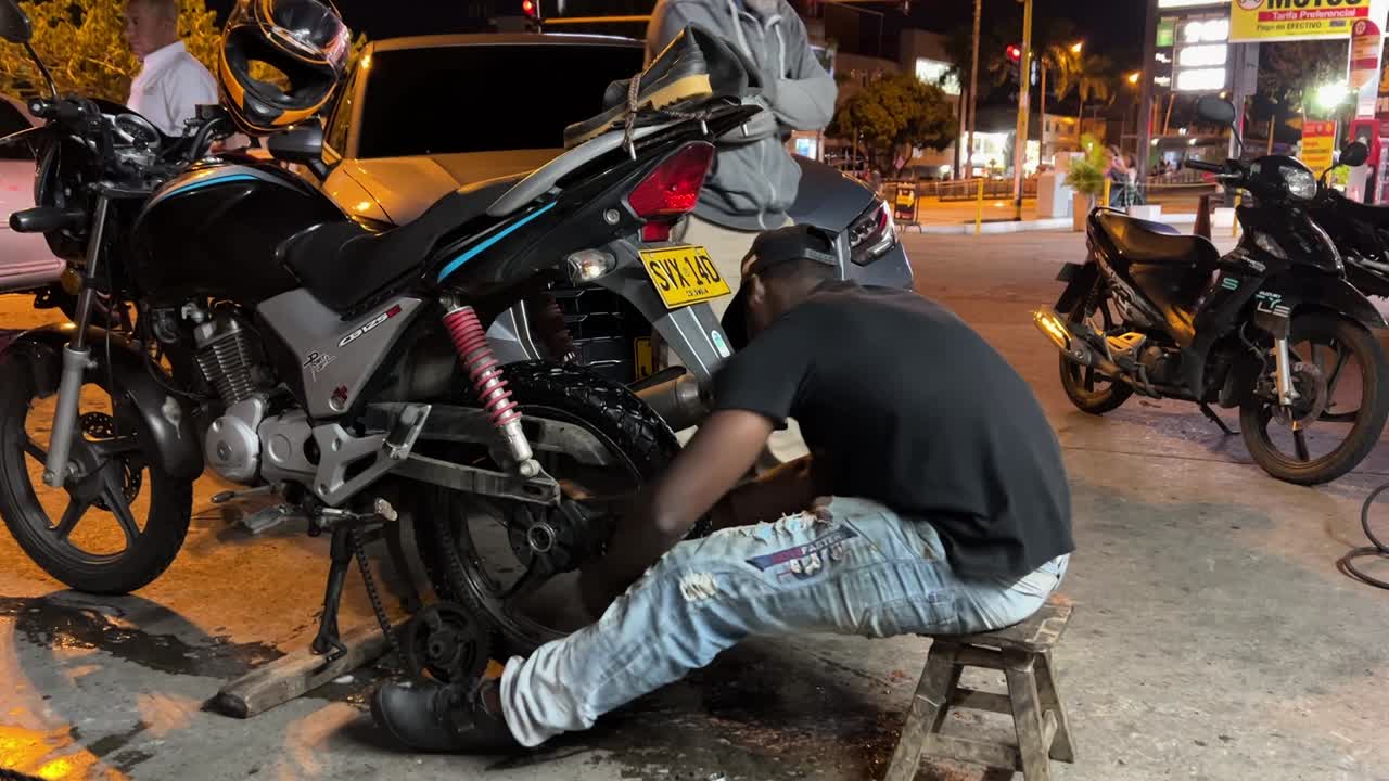 jovem mecânico fixando uma roda de motocicleta em um homem de serviço de posto de gasolina