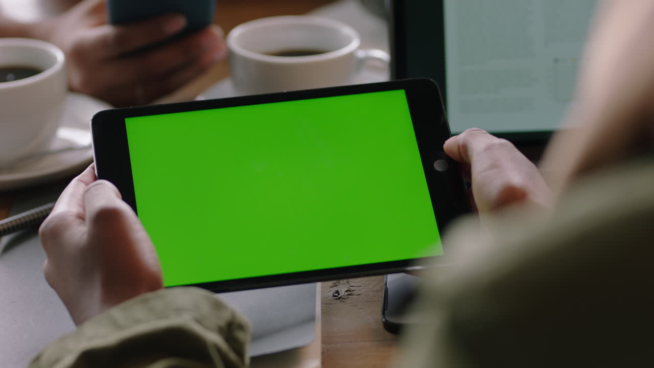 mujer de negocios que usa una tableta viendo la pantalla verde en un dispositivo móvil clave de croma disfrutando del entretenimiento en línea leyendo publicidad en redes sociales en un café de cerca