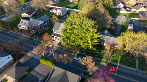 panoramic aerial view, cars driving streets of an american residential town usa, houses, yards in warm spring, drone tracking automobiles