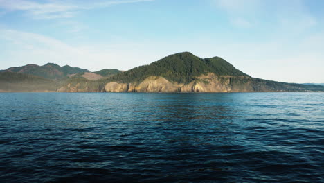 Aerial-view-hovering-over-calm-surface-of-Pacific-Ocean,-looking-towards-Oregon-Coast