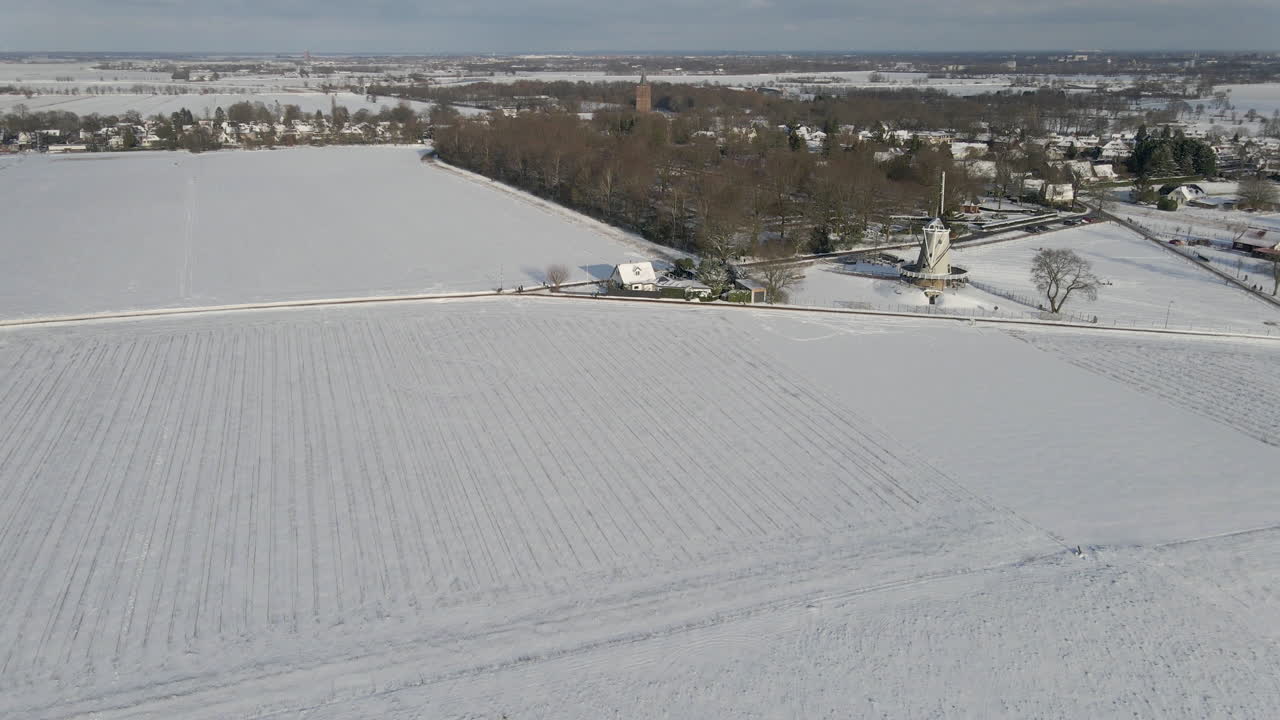Aerial of beautiful snow covered rural landscape with a traditional windmill at the edge of small town
