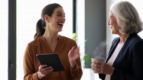 businesswoman laughing with senior colleague during coffee break