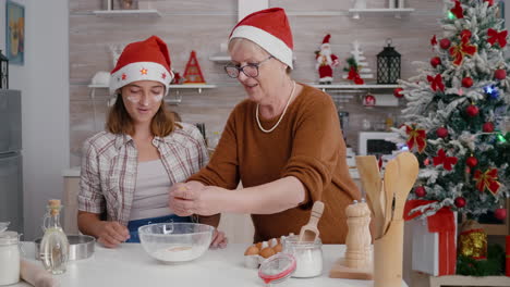 nieta con nieta rompiendo huevo en el cuenco de la cocina con ingrediente de harina