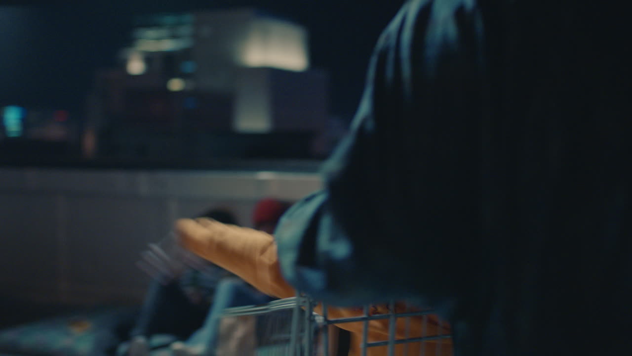 행복 한 친구 들 의 그룹 이 쇼핑 카트 를 가지고 놀고 밤 에 지붕 에서 즐겁게 주말 축하 파티 를 즐기고 있다