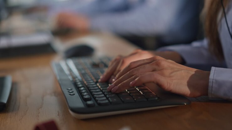 Callcenter-MitarbeiterIn tippt auf einem Computer und nimmt eine Online-Bestellung im Büro entgegen, Nahaufnahme