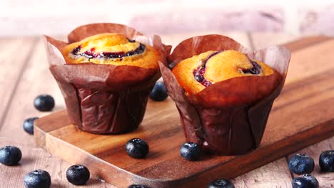 two blueberry muffins on wooden board