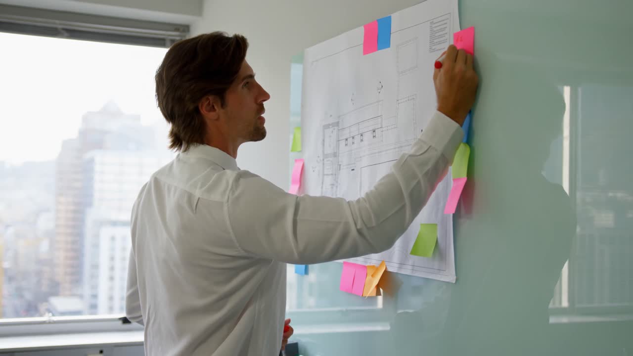 Side view of young Caucasian male executive working on glass board in a modern office 4k