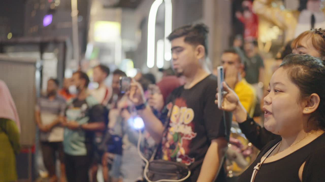 Tourists enjoying local artists busking on Kuala Lumpur streets in Malaysia. Night view.