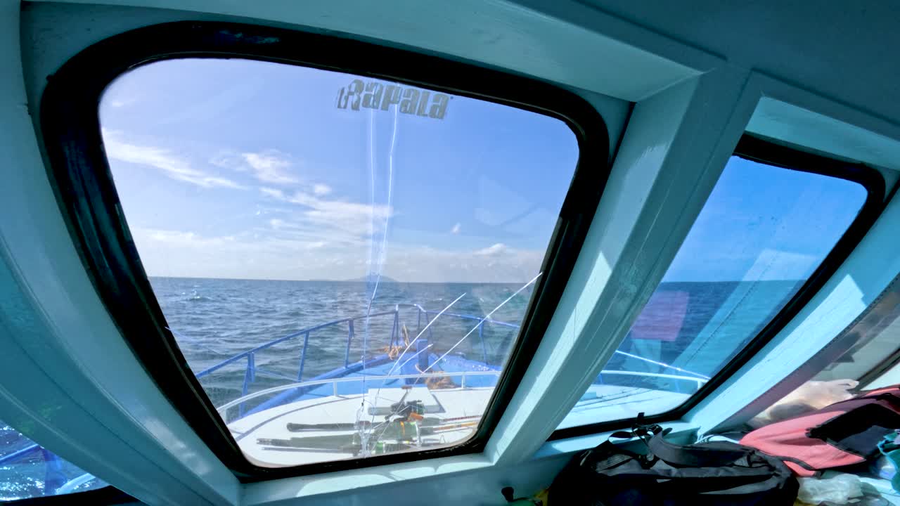 Cockpit interior overlooks ocean waves, fishing rod, and bright daylight through broken window, Phuket