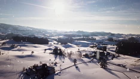 Edificios-De-Aldea-En-Un-Paisaje-Montañoso-Cubierto-De-Nieve-Durante-Las-Nevadas,-Vista-Aérea-De-Drones