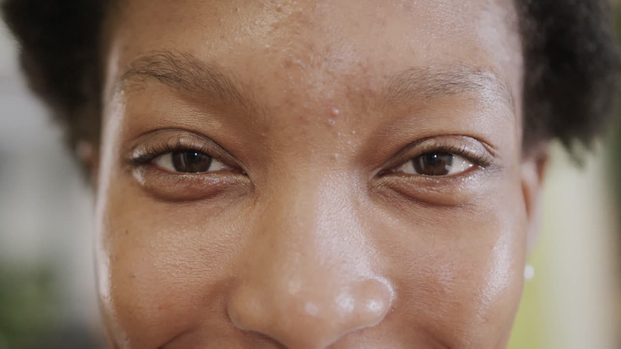retrato de cerca de los ojos de una feliz mujer de negocios afroamericana en la oficina, en cámara lenta
