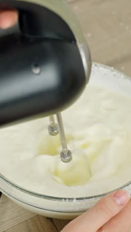 close-up vertical shot of cream being mixed, an essential step in making tiramisu dessert.