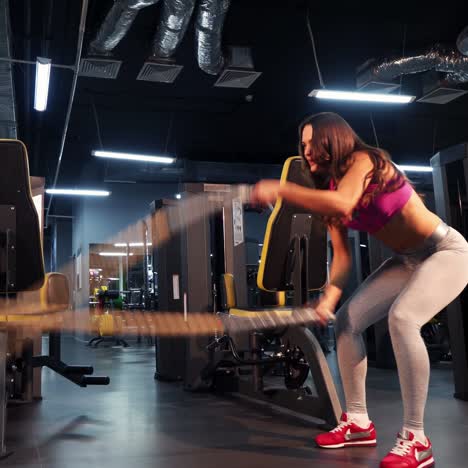 battle ropes session. attractive young and athletic girl using training ropes in a gym.