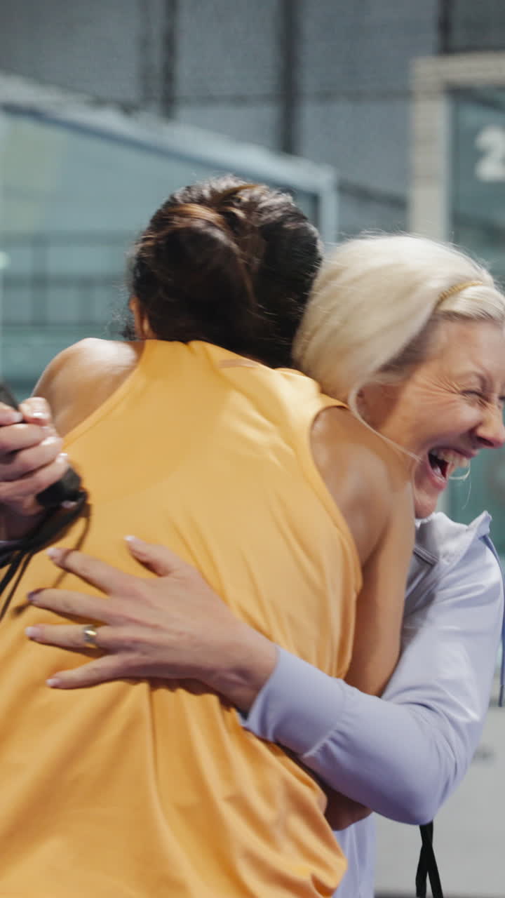 Due donne che si abbracciano e celebrano la vittoria su un campo da padel.