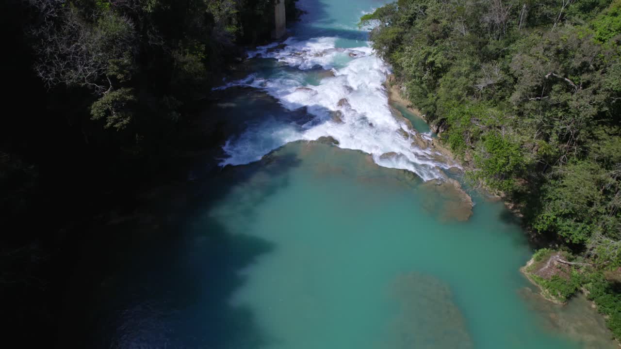 Volando all'indietro da un ponte che attraversa un fiume dalle acque turchesi nel mezzo della giungla del Chiapas, Messico.