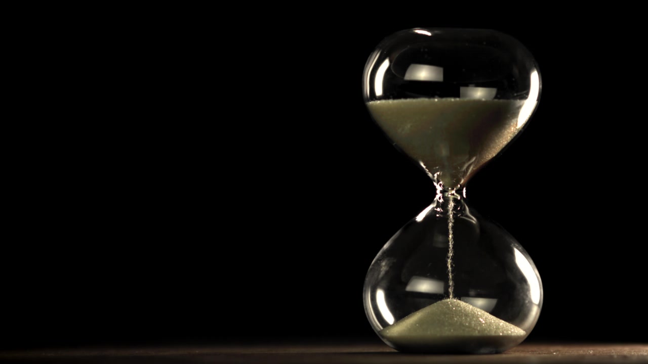Sand Flowing Through an Hourglass on a Dark Background