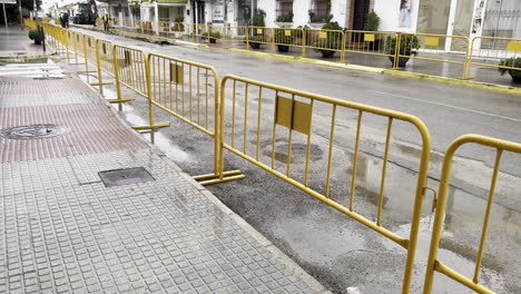 yellow barriers line a wet street, creating a designated construction or restricted area
