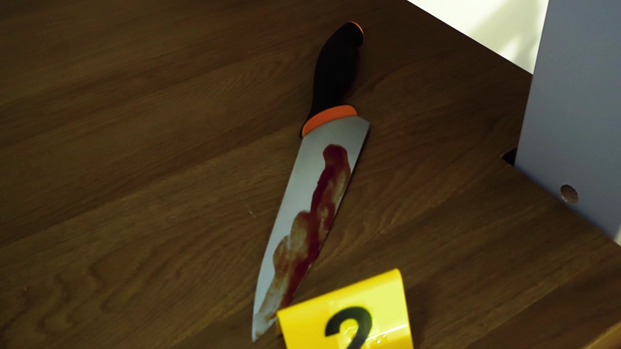 Cuchillo ensangrentado yaciendo en unas escaleras de madera en la escena de un crimen, con un marcador de evidencia policial amarillo número dos colocado a su lado por un investigador forense que investiga un caso de asesinato violento.