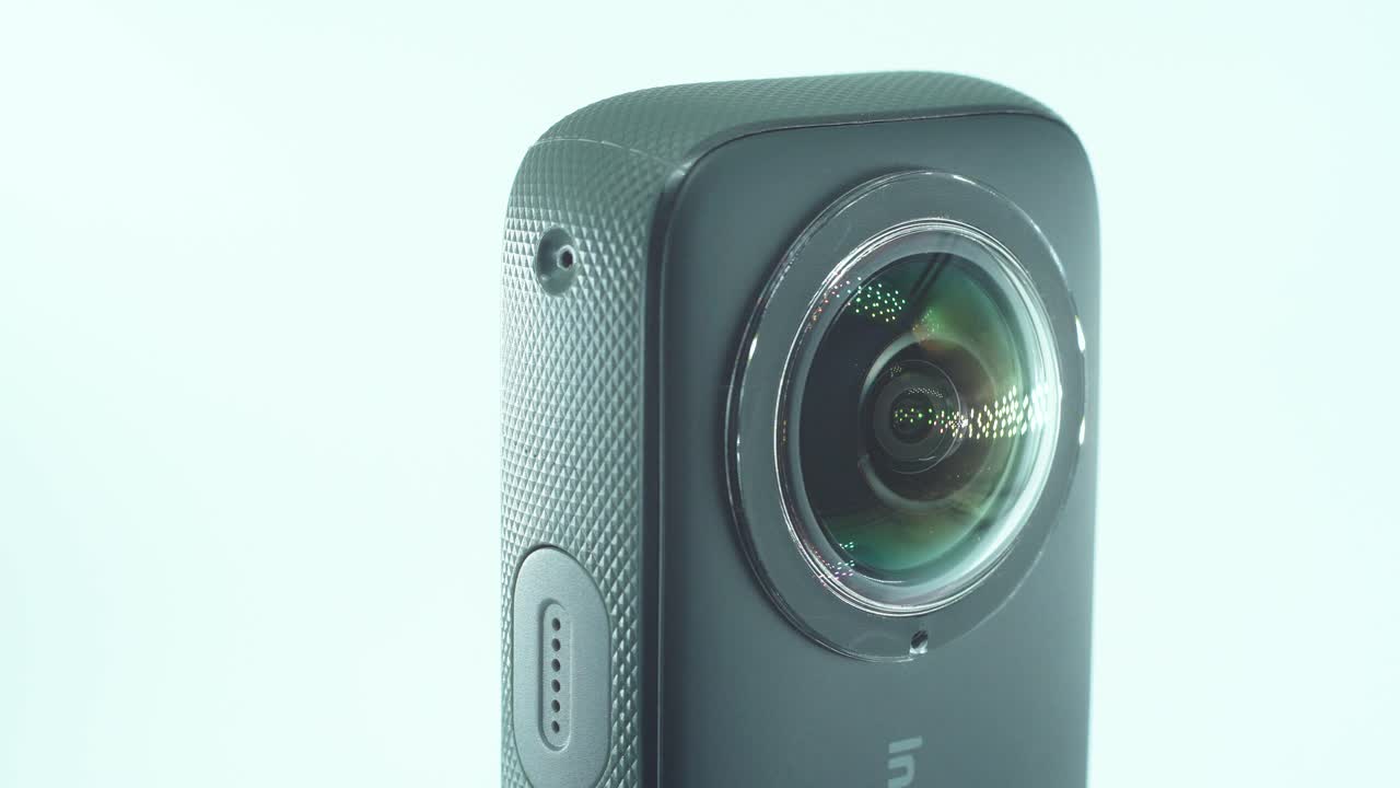 un primer plano de una cámara 360 con lente dual, dos cubiertas de lentes, iluminación de estudio brillante que refleja, en un soporte giratorio, cámara lenta, video de 4k