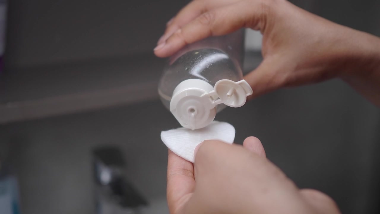 Person Pouring Skincare Toner onto Cotton Pad