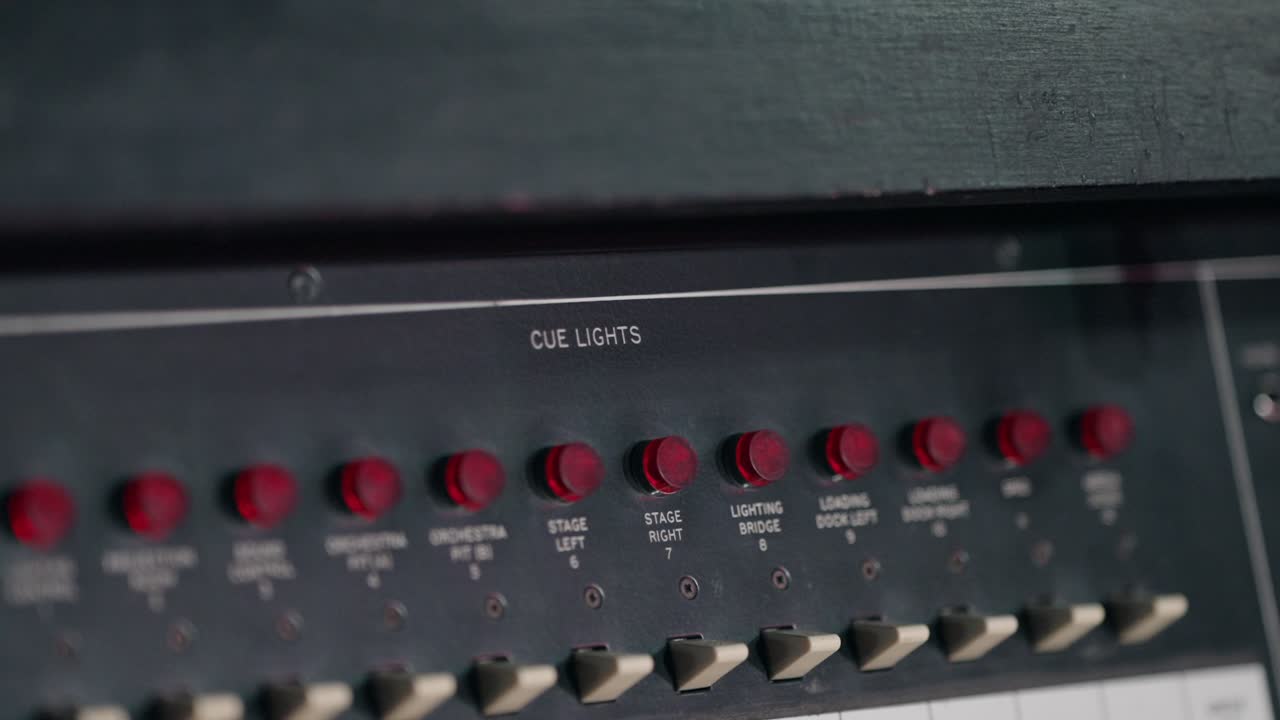 Close up of an old cue light control panel with red switches and worn buttons
