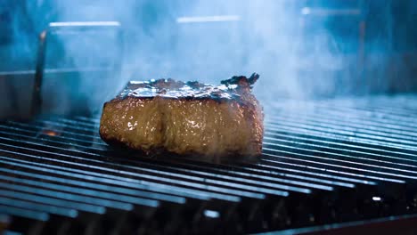 Bistec-Grande-A-La-Parrilla,-Hay-Humo-De-Las-Brasas-A-La-Carne,-Vista-Lateral,-Primer-Plano-4k-Bistec-Con-Una-Vista-Muy-Sabrosa-4k