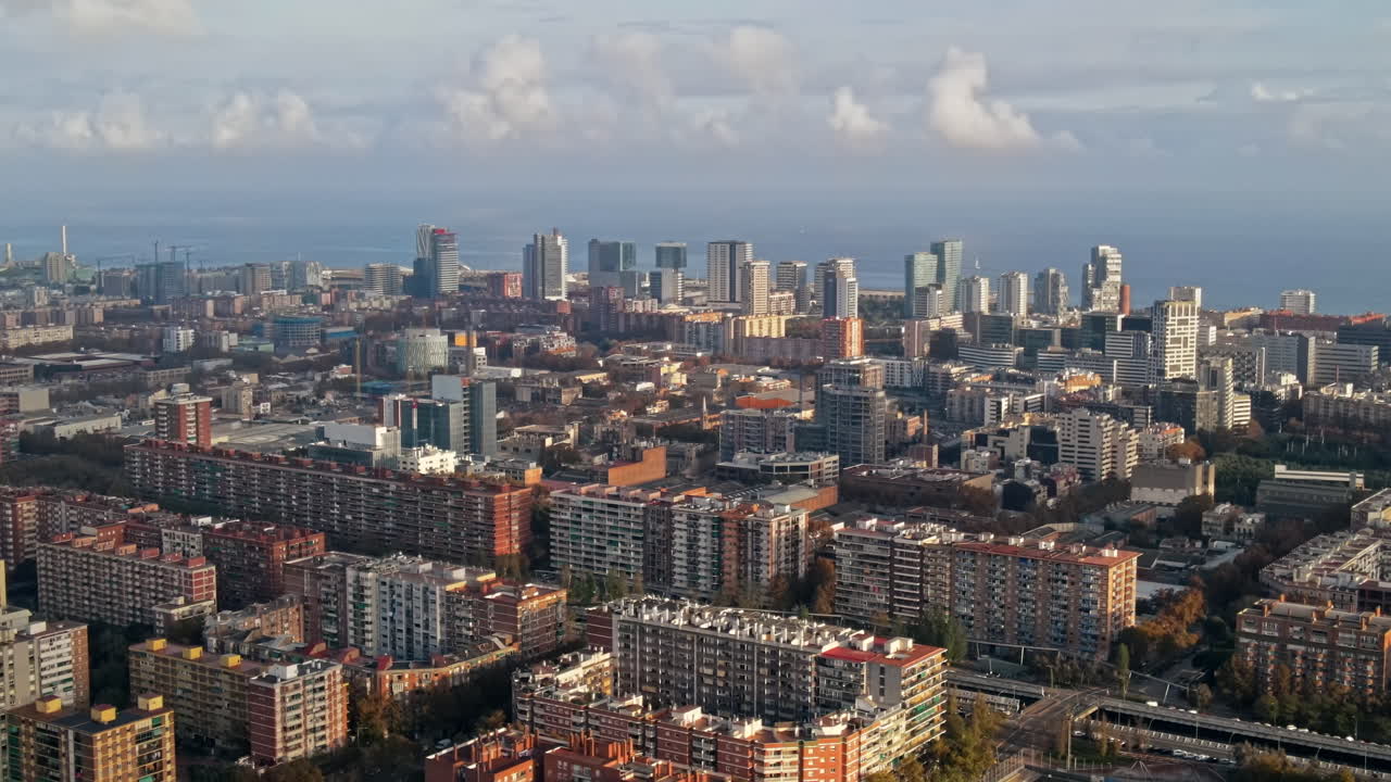 Letecký pohled na Barcelonu, Španělsko. Mnoho obytných a kancelářských budov, Středozemní moře v dálce.