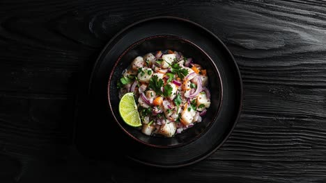 ceviche frais avec du citron vert dans un bol noir sur un fond sombre