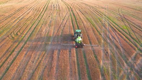 tractor pulveriza tierras de cultivo cultivadas, captura aérea de seguimiento al atardecer