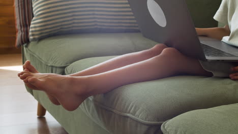 close up of the feet of a little girl with the laptop on her lap