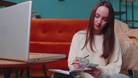 Woman-doing,-planning-home-budget-on-laptop-and-counting-money,-girl-checking-dollar-cash-income