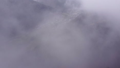 Aerial-reveal-view-of-a-mountain-village-below-clouds-during-autumn-fall-in-Vosges,-France