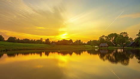 Zeitraffer-Eines-Ländlichen-Gehöfts,-Während-Sich-Sonnenuntergang-Und-Wolken-Auf-Spiegelähnlichem-Wasser-Spiegeln