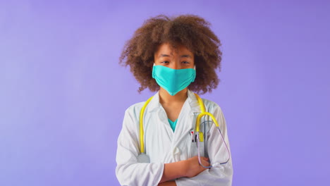 studio portrait of boy dressed as doctor or surgeon against purple background
