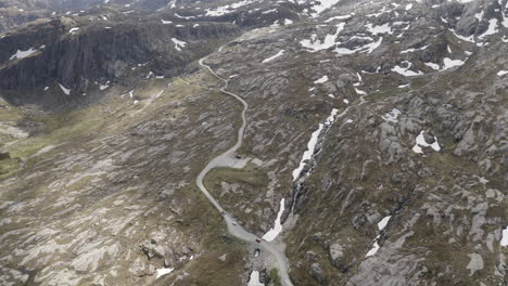 drone shot of three cars driving on a small road in the beautiful nature of norway