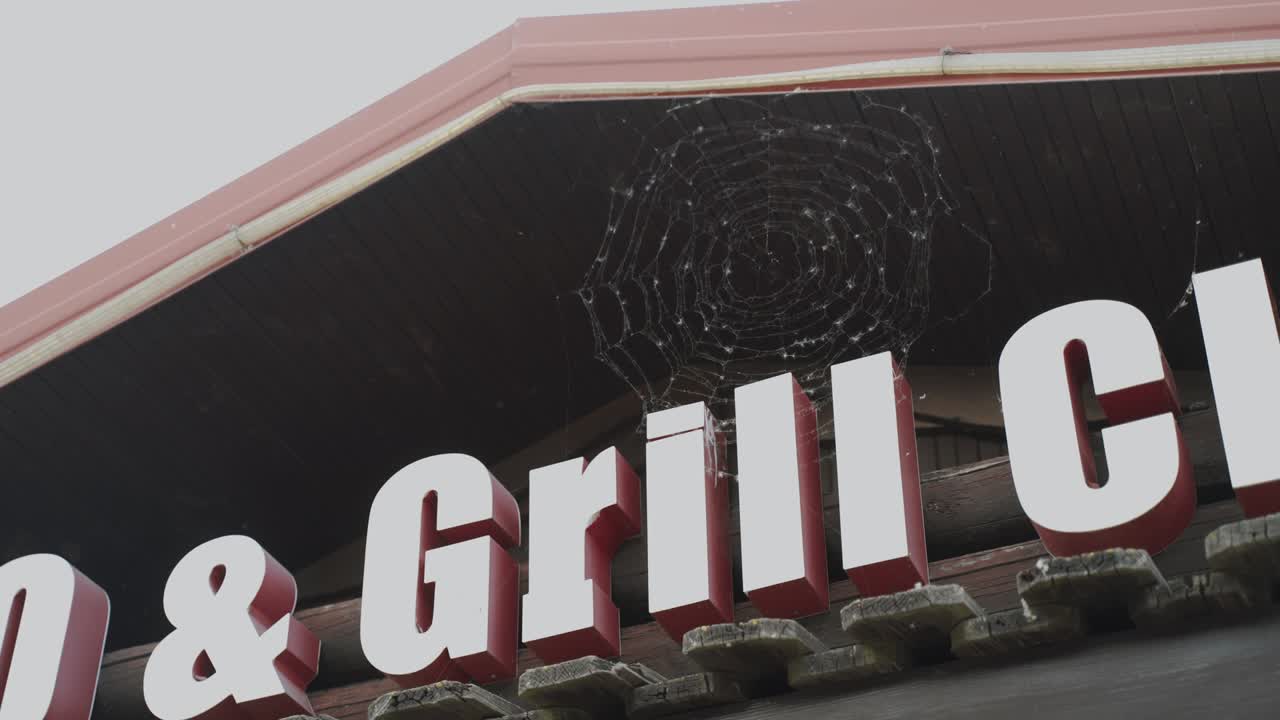 지붕 아래의 털에 거미줄이 있는 3차원 글자로 만든 표지판.